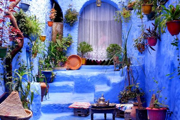 The enchanting blue streets of Chefchaouen, Morocco, lined with colorful pottery and vibrant doors.